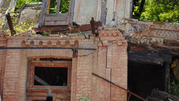 Ukrayna 'da yanan duvarları ve çökmüş çatısı olan savaş hasarlı ev cephesi.