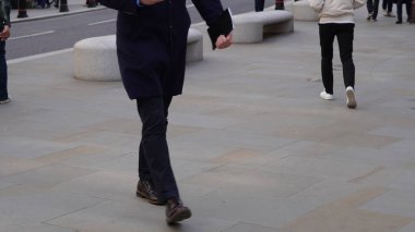 Şehir ortamında isimsiz bir kalabalık yürüyor..