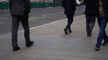 Şehir ortamında isimsiz bir kalabalık yürüyor..