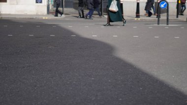 Şehir ortamında isimsiz bir kalabalık yürüyor..