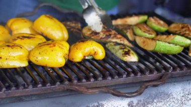 Açık hava vejetaryen barbeküsünde şefin çevirdiği ızgara kabak ve sebzeler.