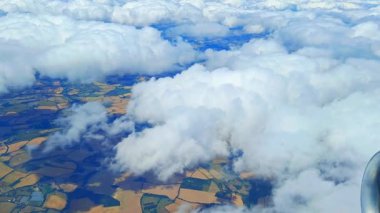Bulutların üzerindeki huzurlu uçuş sırasında uçak penceresinden bulutlu gökyüzü manzarası. Pencere kenarındaki kabarık bulutların manzarası ile seyahat uçuşunu rahatlatıyor.