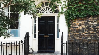 Geleneksel simetrik tasarımı olan eski Londra evinin siyah ön kapısı