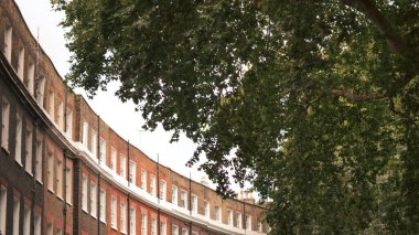 Kemerli kapısı ve klasik beyaz çerçeveli pencereleri olan tarihi kırmızı tuğlalı İngiliz evi..