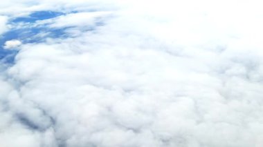 Uçuş sırasında uçak penceresinden beyaz bulutlar, temiz gökyüzü ve seyahat manzarası