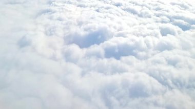 Uçuş sırasında uçak penceresinden beyaz bulutlar, temiz gökyüzü ve seyahat manzarası