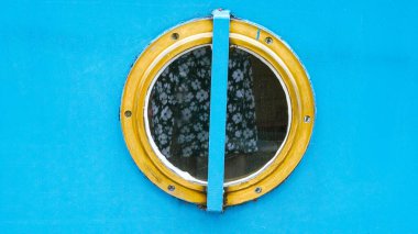 Turist gezisi sırasında güneşli bir günde deniz manzaralı mavi yuvarlak tekne penceresi..