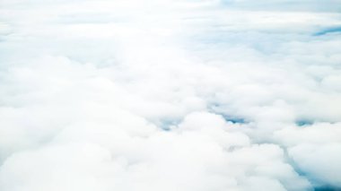 Sakin mavi gökyüzü ve güneş ışığıyla uçak penceresinden hafif bulutlu manzara