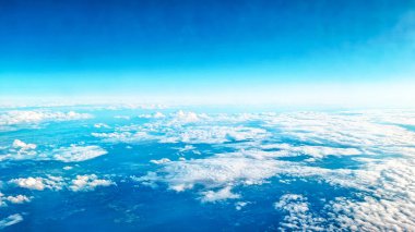 Yüksek uçan ticari uçak penceresinden görülen yumuşak bulut katmanlarının hava görüntüsü.