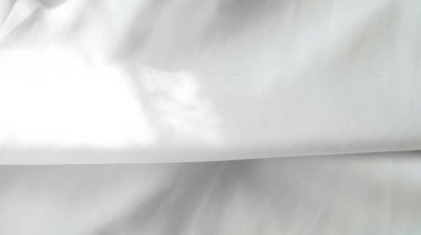 Zarif yumuşak kıvrımları olan parlak beyaz ipek arka planda parlak sert ışık.