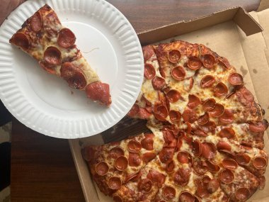 Karton kutuda büyük bir biberli pizzadan bir dilim pizza servis ediyorum.