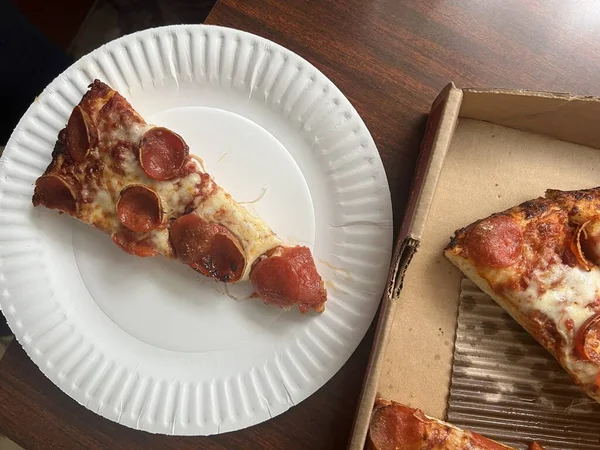 Slice of pepperoni pizza on paper plate.