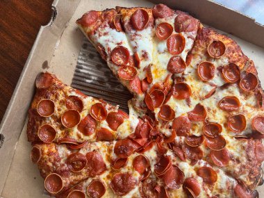 Mukavva bir kutuda peynirli büyük bir biberli pizzadan bir dilim pizza eksik. Bir restorandan paket servis..