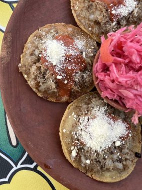 Geleneksel garnachas Meksika, Oaxaca 'daki bir restoranda kil tabakta servis yapıyordu. Masada bol yağda kızartılmış biftek ve salsa peyniri. Üst Görünüm.