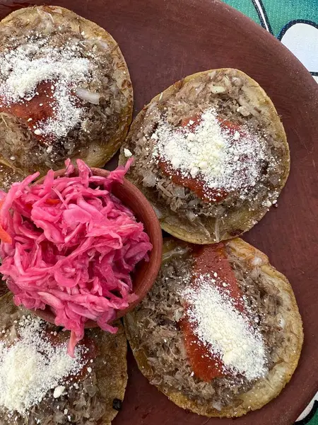 Geleneksel garnachas Meksika, Oaxaca 'daki bir restoranda kil tabakta servis yapıyordu. Masada bol yağda kızartılmış biftek ve salsa peyniri. Üst Görünüm.