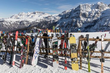 MADONNA DI CAMPIGLIO, ITALY - 26 HAZİRAN 2023: kayaklar ve snowboardlar ahşap bir stantta dinleniyor. Uzakta Grosste eyerini ve yamaçlarını görebilirsiniz..