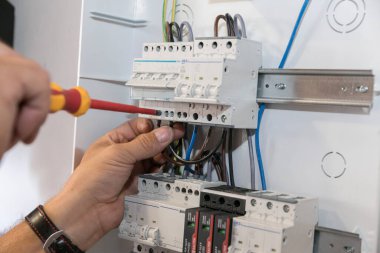 Devre kesici kurulumu. Bir teknisyen kabloları devre kesiciye takıyor. Güneş enerjisi santralini evin elektrik ağına bağlıyorum..
