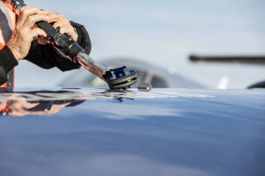 Uçağı dolduruyorum. FBO kalkıştan önce iş uçağına yakıt ikmali yapıyor. Tank tabancalı bir elin yakın çekimi. Kurumsal uçuş kavramı.