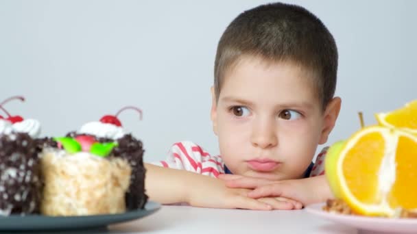 Ένα Πεντάχρονο Αγόρι Κάθεται Ένα Τραπέζι Κοντά Κέικ Και Φρούτα — Αρχείο Βίντεο
