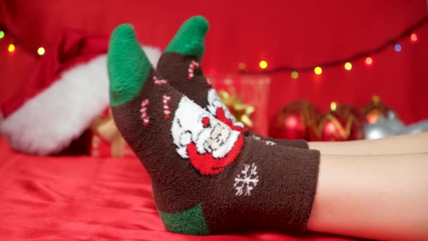 Ноги Теплих Різдвяних Шкарпетках Санта Клаусом Червоному Фоні Чекаючи Свята — стокове відео