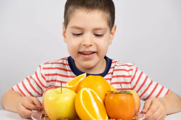 Menino Pré Escolar Olha Para Frutas Laranjas Cáqui Maçãs Fundo — Fotografia de Stock