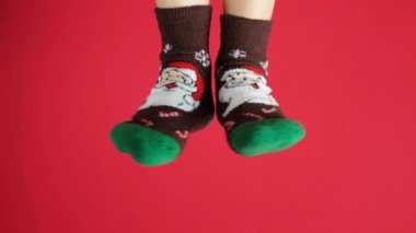 Noel çoraplı kadın ayakları, kırmızı arka planda Noel Baba, dans eden bacaklar..