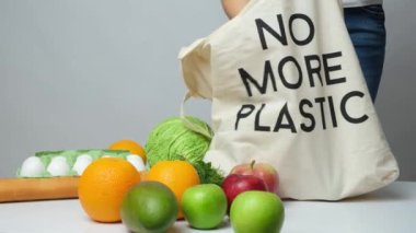 Bir kadın ürünlerini plastik olmayan bir kumaş çantaya koyar. Ekoloji kavramı ve plastiğin reddi