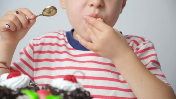 一个5岁的男孩吃蛋糕 舔手指 在衣服上擦脏手 — 图库视频影像