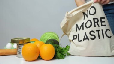 Bir kadın kumaş bir eco çantasından daha fazla plastik metin olmadan yiyecek alışverişi yapıyor..