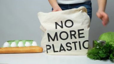Bir kadın kumaş bir eco çantasından daha fazla plastik metin olmadan yiyecek alışverişi yapıyor..
