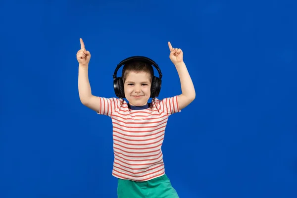 Szczęśliwy Chłopiec Słuchawkach Koszulce Wskazuje Palcami Niebieskim Tle — Zdjęcie stockowe