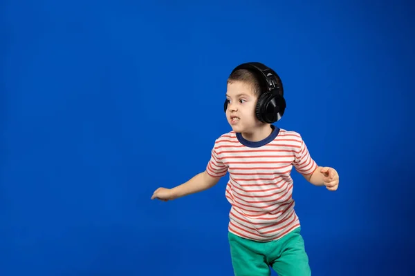 Szczęśliwy Chłopiec Dużych Bezprzewodowych Słuchawkach Działa Patrzy Bok Wskazuje Palcem — Zdjęcie stockowe