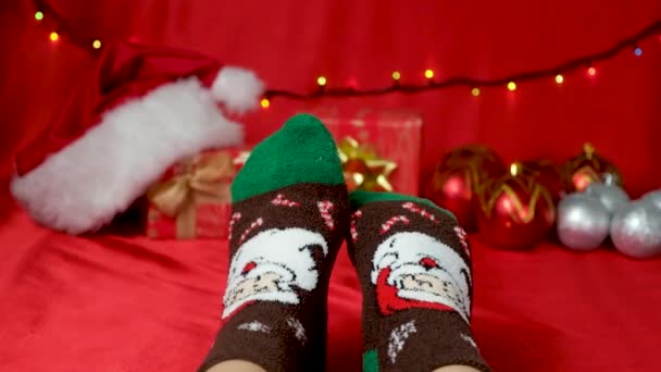 Πόδια Ζεστές Χριστουγεννιάτικες Κάλτσες Τον Άγιο Βασίλη Κόκκινο Φόντο Περιμένοντας — Αρχείο Βίντεο