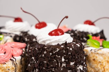 Beyaz arka planda çikolatalı, kirazlı ve kremalı kekler.