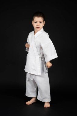 Küçük bir çocuk dövüş sanatları yapıyor, kimono karate dersleri alıyor.