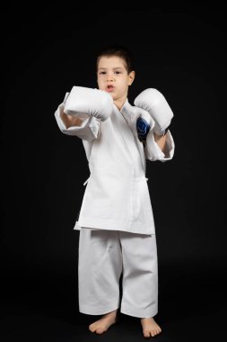 Küçük bir çocuk dövüş sanatları öğreniyor, kimono ve boks eldivenleriyle karate yapıyor.