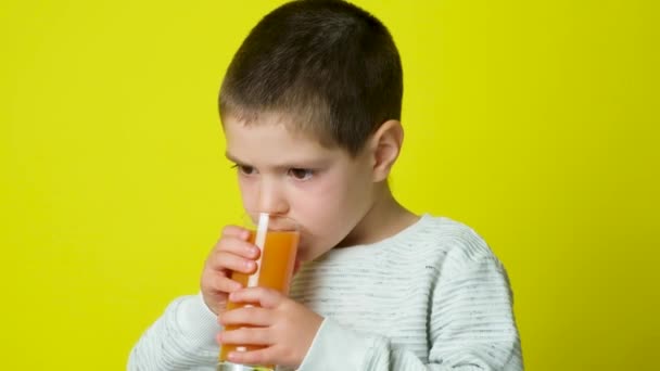 Mooie Jarige Jongen Drinkt Sinaasappelsap Likt Een Gele Achtergrond — Stockvideo