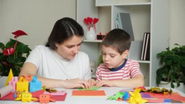 Anne ve oğlu kağıttan, origamiden, hayvan figürleri yaratıyorlar.