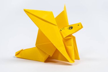 Origami sarı sevimli ejderha, beyaz arka planda kağıttan bir hayvan figürü..