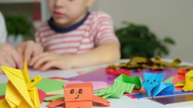 Anne ve oğlu kağıttan, origamiden, hayvan figürleri yaratıyorlar.