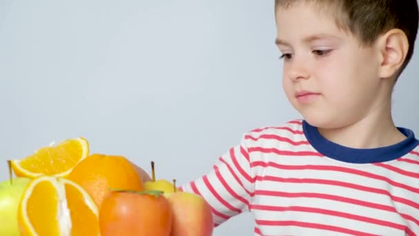 Ragazzino Frutta Bambino Guarda Arance Cachi Mostra Lingua Accigliato — Video Stock