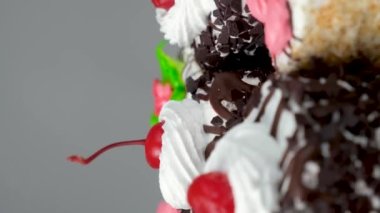 Çikolatalı, kirazlı ve kremalı kekler beyaz arka planda dönüyorlar.