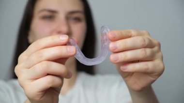 Diş koruyucusu, temporomandibular eklemlerin işlev bozukluğu, bruksisizm, maloklasyon tedavisi için atel gösteren bir kadın, çene kaslarını gevşetmek için.
