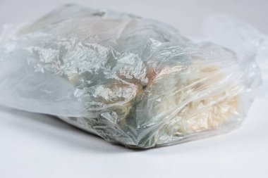 Beyaz arka planda plastik poşette kalıplı ekmek, yakın plan.