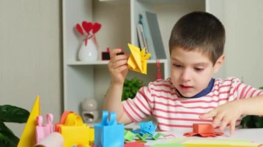 Çocuk ahtapot figürleri ve origami kağıdından yapılmış bir ejderhayla oynuyor.