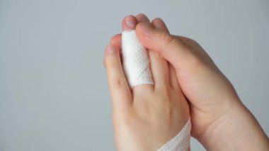 Parmakta yaralanma, kolda beyaz bir arka planda bandaj. Kırık, kemikte çatlak, parmak ekleminde travma.
