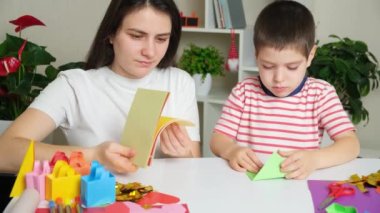 Anne ve oğlu kağıttan, origamiden, hayvan figürleri yaratıyorlar.