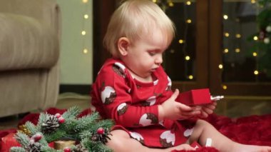 Sarışın, küçük bir kız çocuğu Noel oyuncakları, bokeh çelenkleri, çocuklar ve yeni yıl arifesi oynuyor..