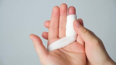 Parmakta yaralanma, kolda beyaz bir arka planda bandaj. Kırık, kemikte çatlak, parmak ekleminde travma.