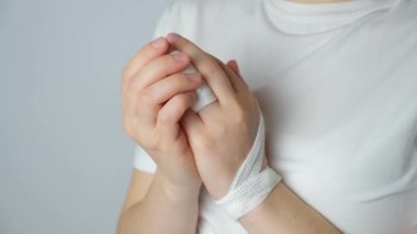 Parmakta yaralanma, kolda beyaz bir arka planda bandaj. Kırık, kemikte çatlak, parmak ekleminde travma.